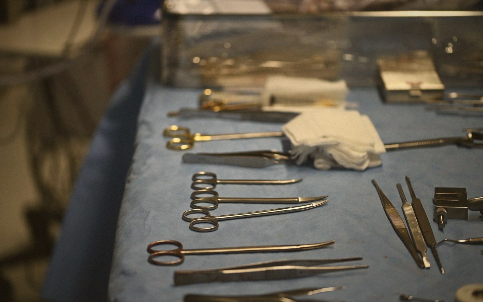 Surgical forceps and scissors arranged on a blue sterile drape