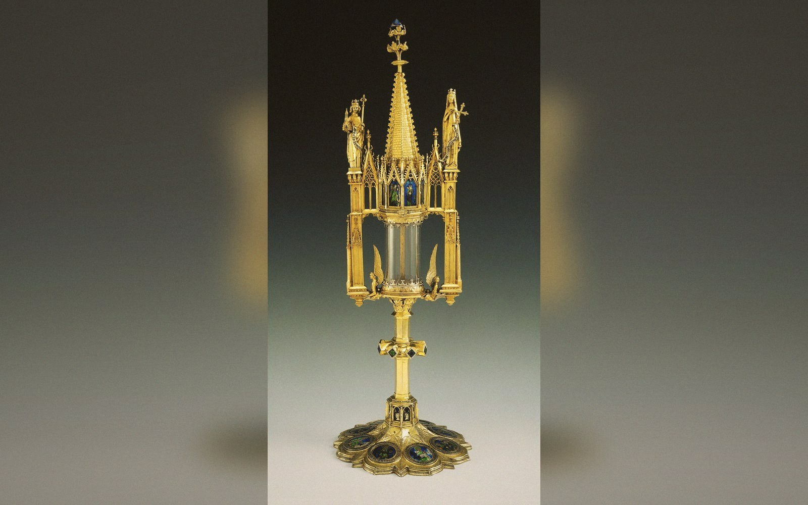 Gilded gothic reliquary with spire, glass cylinder and enameled base